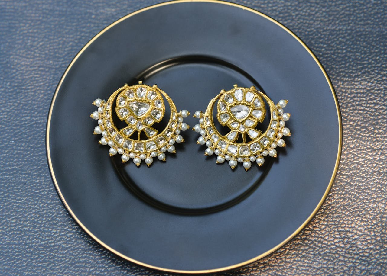 Luxurious gold and pearl earrings elegantly displayed on a black plate, perfect for jewelry showcases.