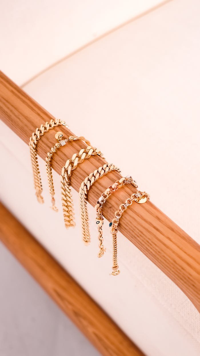 Stylish gold bracelets elegantly draped over a wooden rod, showcasing luxury and style.