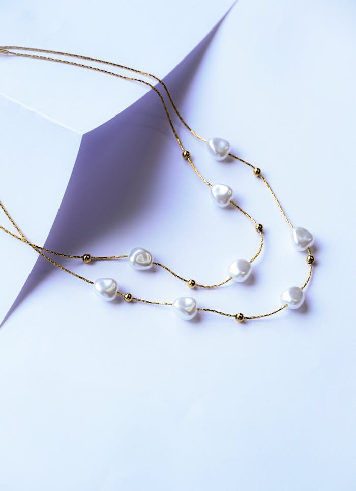 Stylish gold necklace with pearls on white background, perfect for fashion photography.